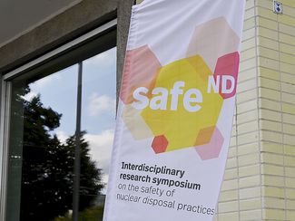 Am Eingang zum Veranstaltungsort hängt ein Banner mit dem Logo des Forschungssymposiums.